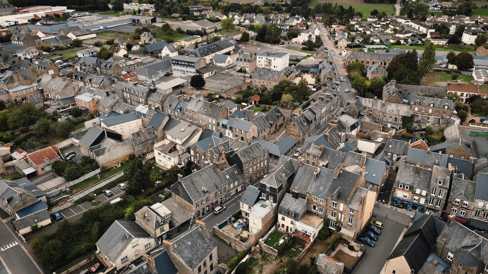 Vue aérienne d’un quartier de maisons serrées aux toits d’ardoise, de pentes et de hauteurs variées.